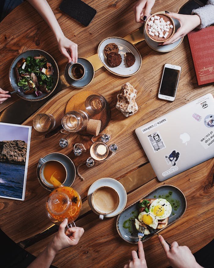 A group enjoying a diverse brunch spread with coffee on a rustic wooden table. Perfect for food and lifestyle themes.